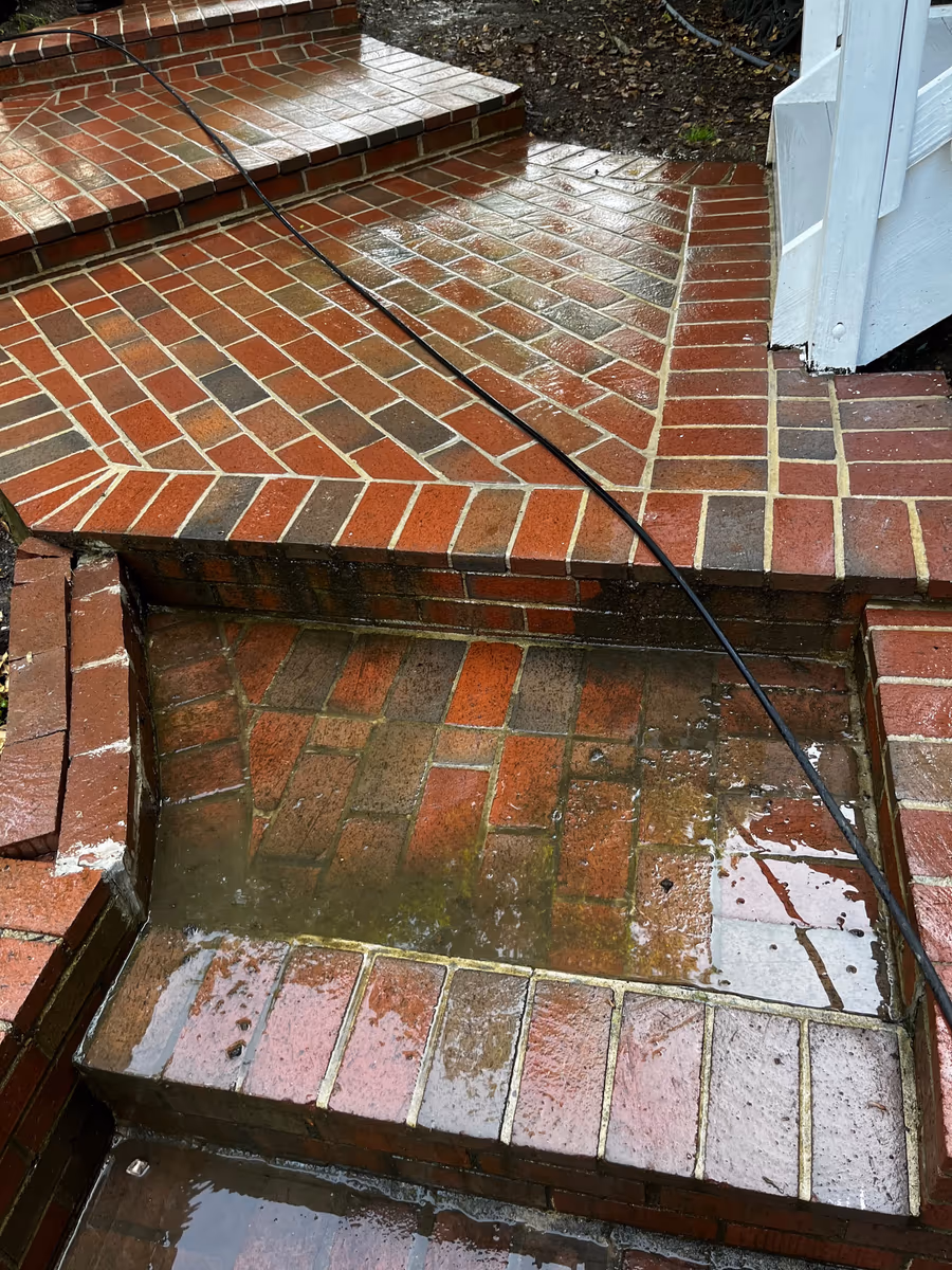Brick steps mid-wash, the cleaned treads contrasting with the stained ones below