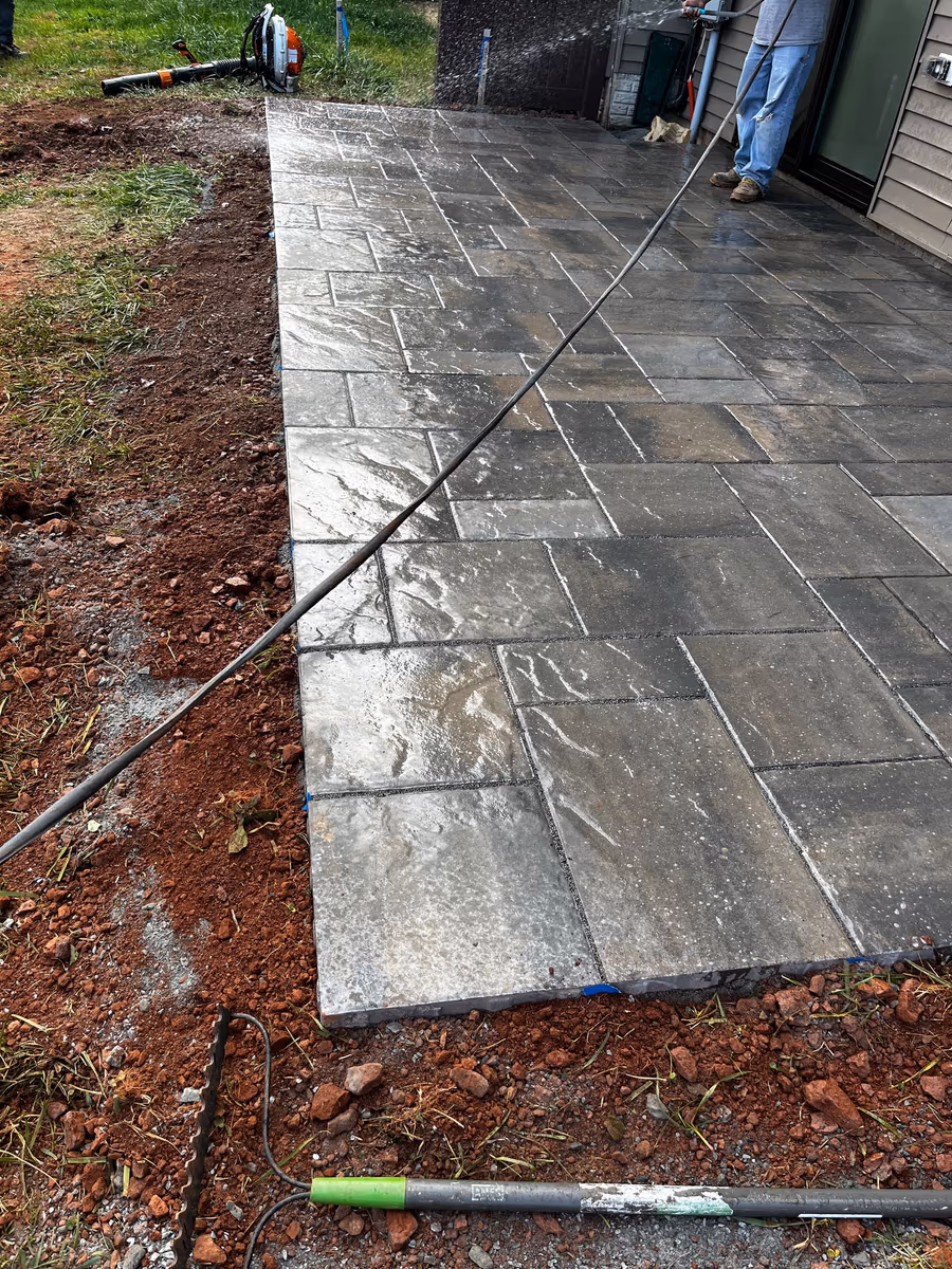 Flagstone patio being power washed, dirt lifting off the stone in a clean line