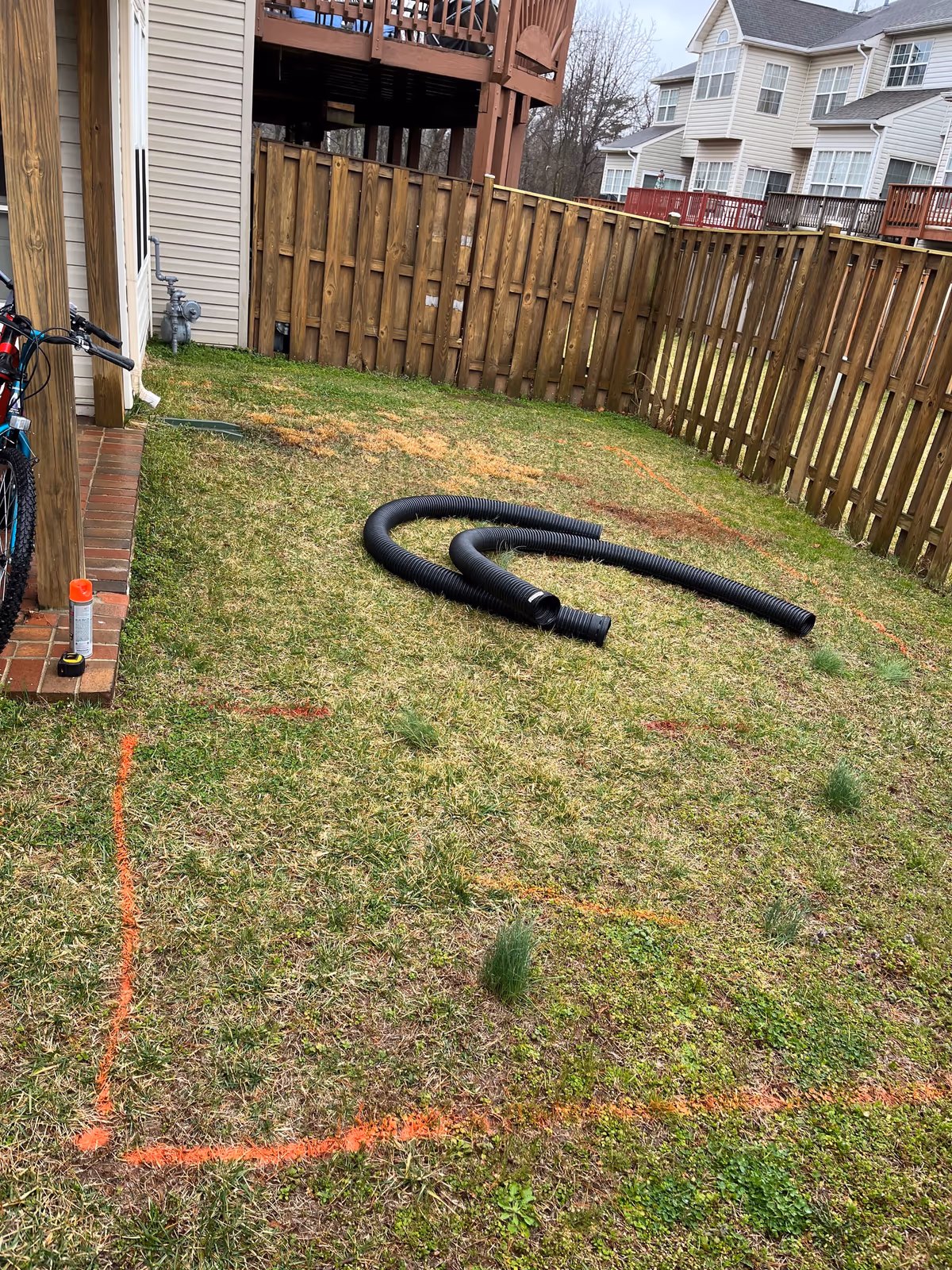 Back yard marked out with layout paint and drainage pipe before patio construction