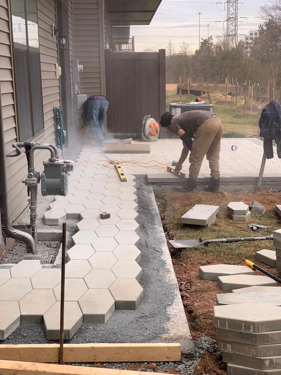Hexagonal pavers being cut and set in place during a patio installation