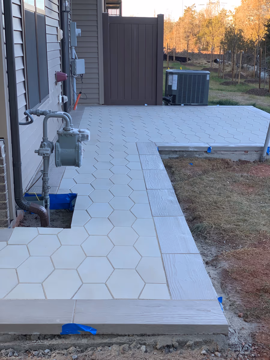 Completed light paver patio and connecting walkway beside a home